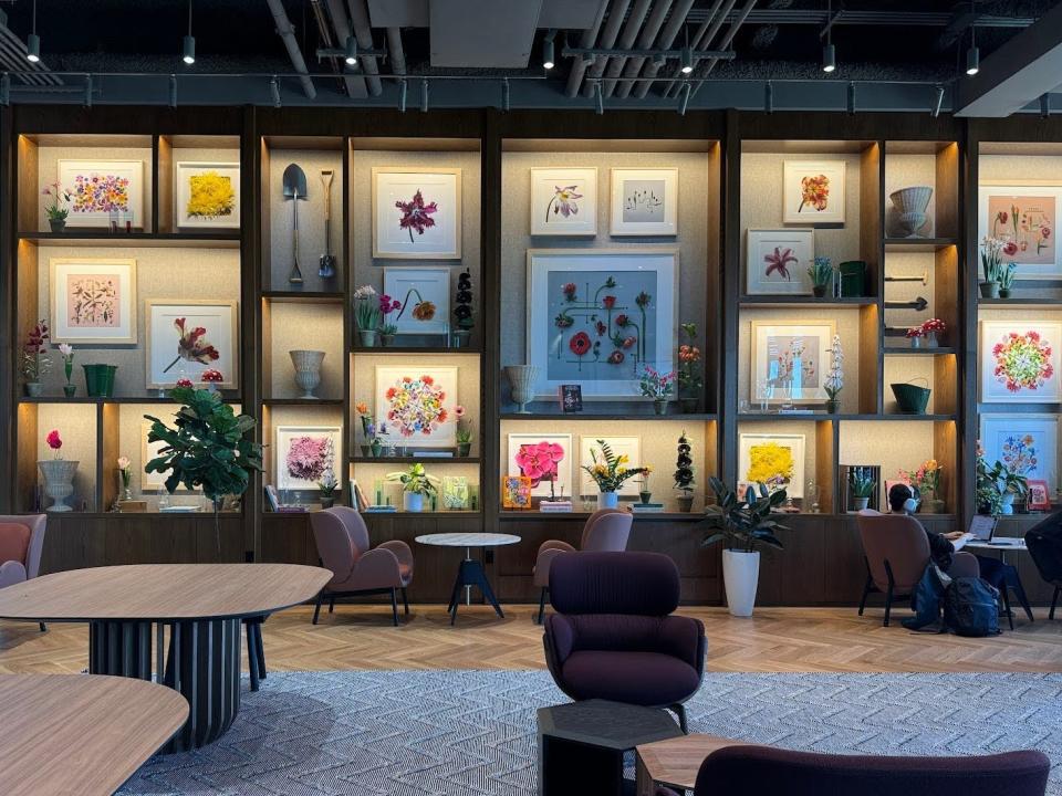 One of the coworking spaces, with tables and couches and decorated with artwork of flowers