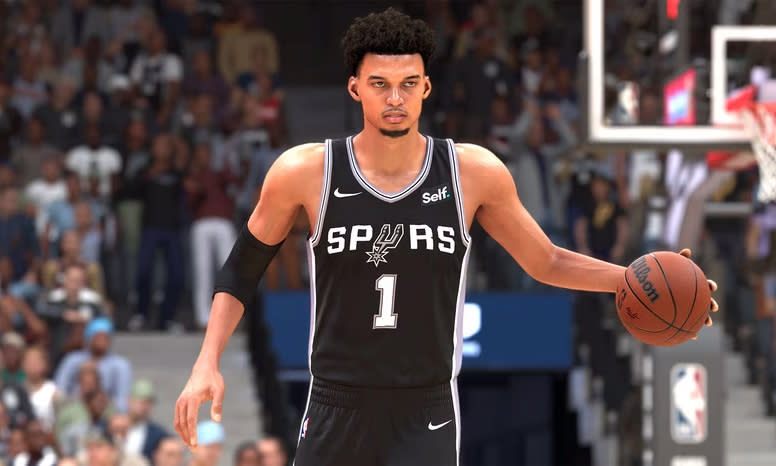 Promotional screenshot from NBA 2K24, featuring the Spurs' rookie Victor Wembanyama dribbling the ball up the court. Stadium full of fans visible behind him.