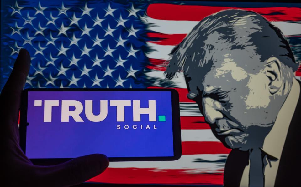 Truth Social logo displayed on a smart phone with Donald J. Trump seen in the background, in this photo illustration. On 03 September 2023 in Brussels, Belgium