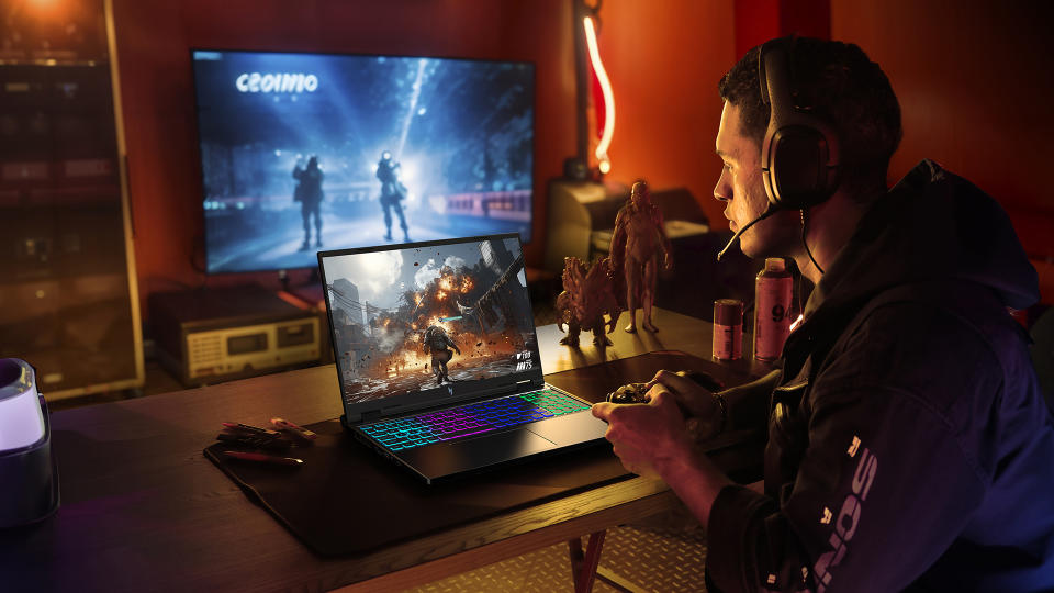 A gamer sits in a posh, modern-lit gaming room with an Acer gaming laptop. A second TV shows a different part of a game behind them.