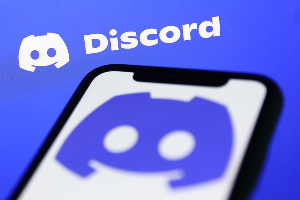 Discord logo displayed on a phone screen and Discord website displayed on a screen in the background are seen in this illustration photo taken in Krakow, Poland on November 5, 2022.