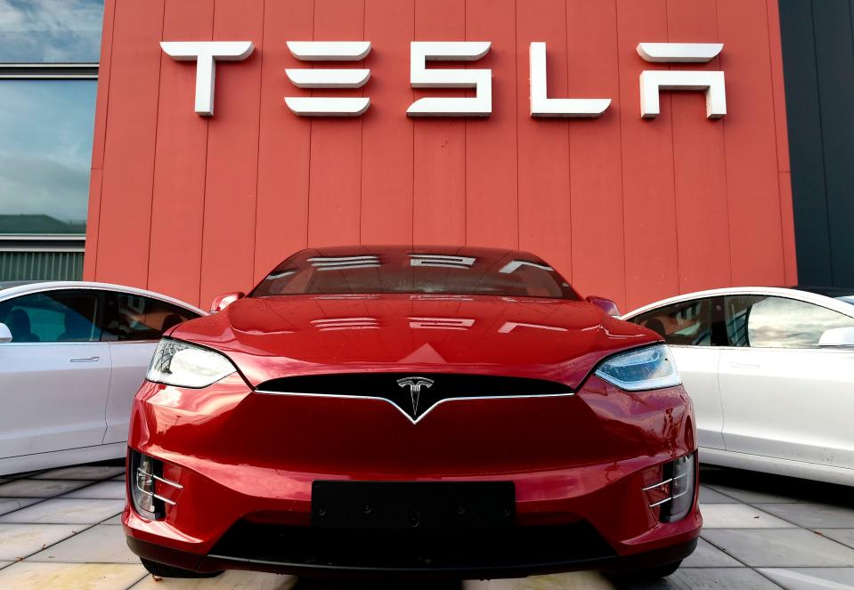 A red Tesla outside a Tesla showroom.