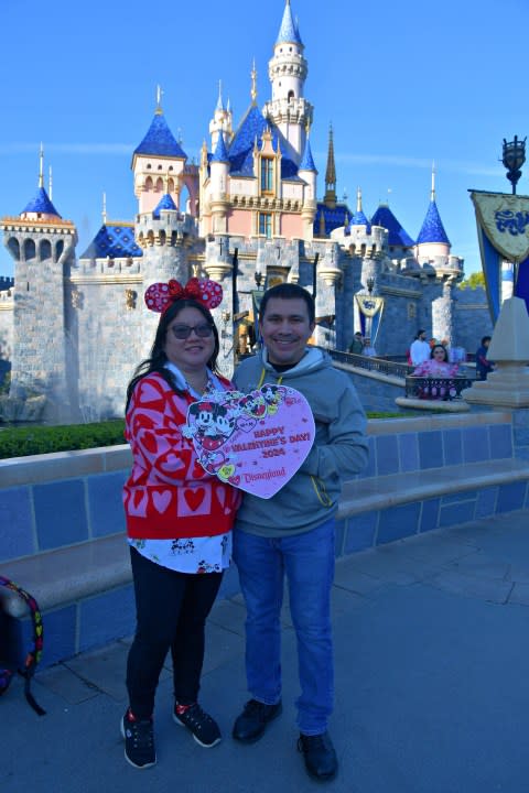Couple in front of castle at Disneyland on Valentine's Day.