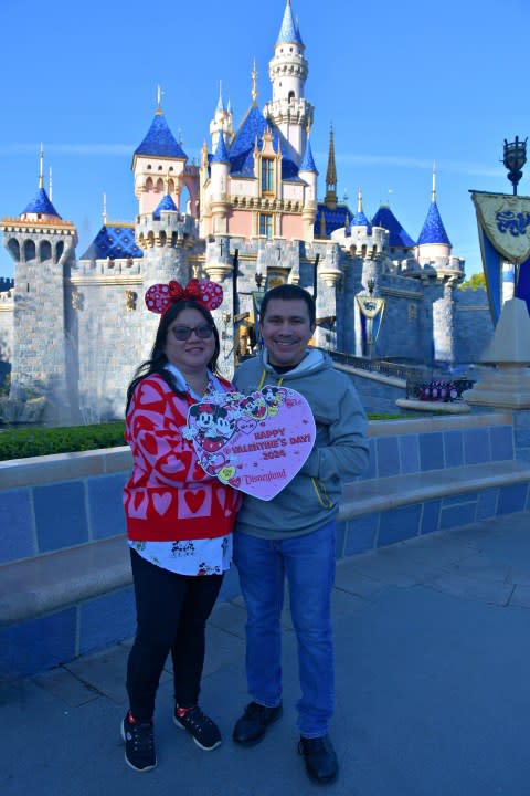 Couple in front of castle at Disneyland on Valentine's Day.
