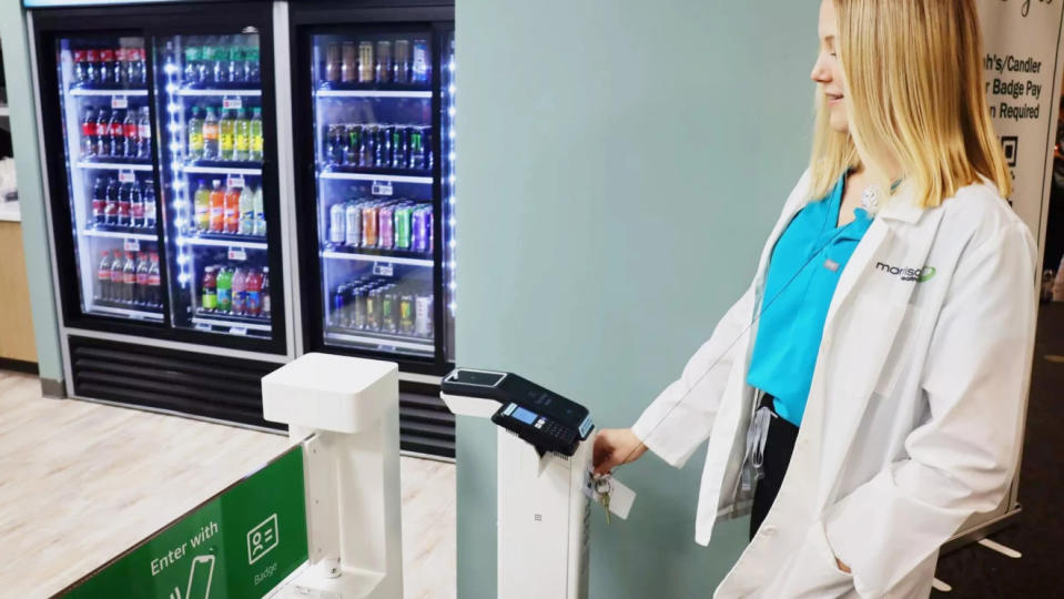 A medical workers scans a badge at an Amazon-powered Just Walk Out kiosk in a hospital.