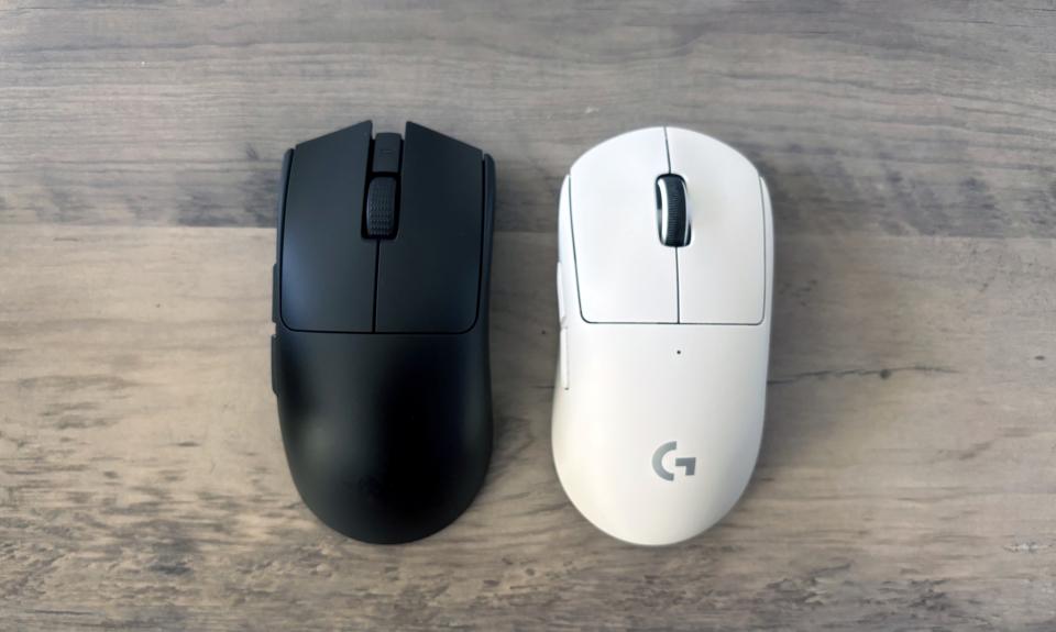 A black Razer Viper V3 Pro gaming mouse and a white Logitech G Pro X Superlight 2 gaming mouse rest side-by-side on top of a brown wooden table.