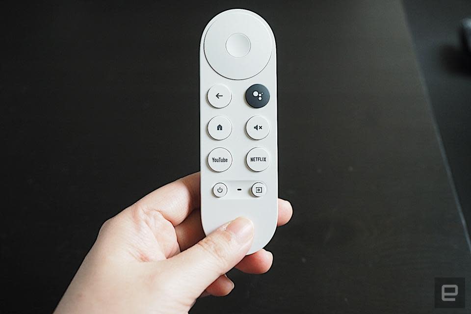 Voice remote for the Chromecast with Google TV (HD) remote. A person’s hand holds the white-colored remote against a dark background.