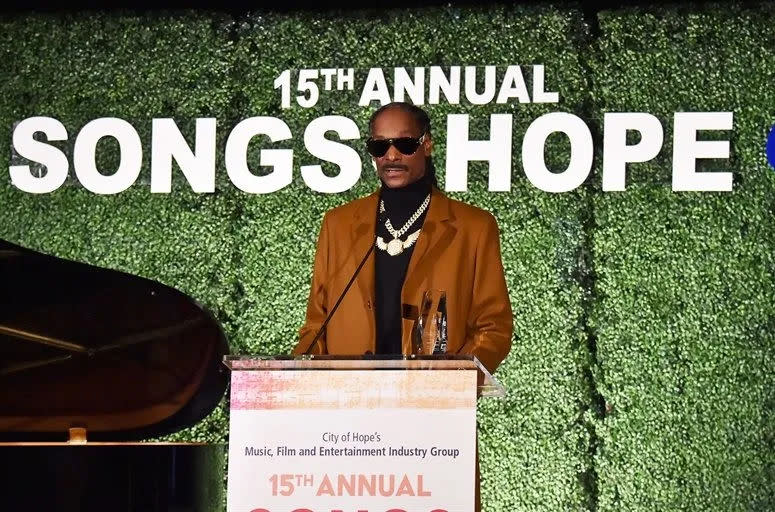 Rapper Snoop Dogg stands at a podium with the text 