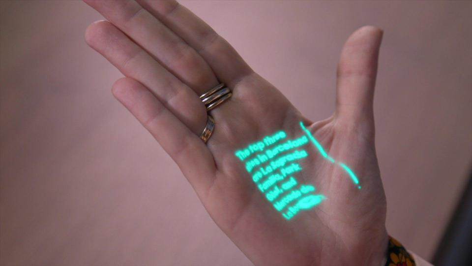 The Humane AI pin's laser ink display projection on a hand at Mobile World Congress 2024