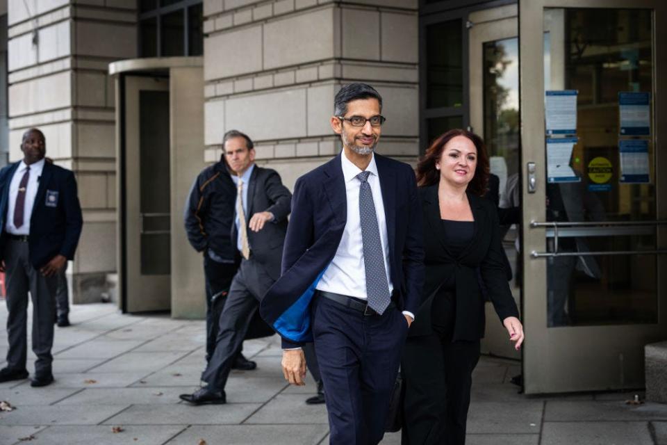 Google CEO Sundar Pichai smiles while walking past security personnel outside a federal courthouse in Washington, DC, after testifying in an antitrust case.